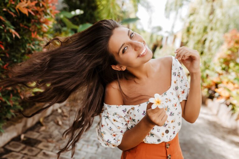 Lady with white flower in her hand plays with hair
